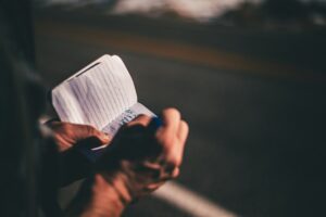 Hands review an insurance card beside a policy document and smartphone on a kitchen table.